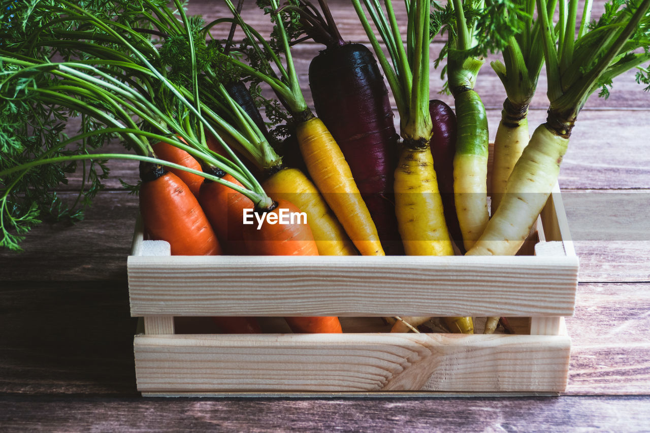 Colored carrots in wooden box on kitchen table