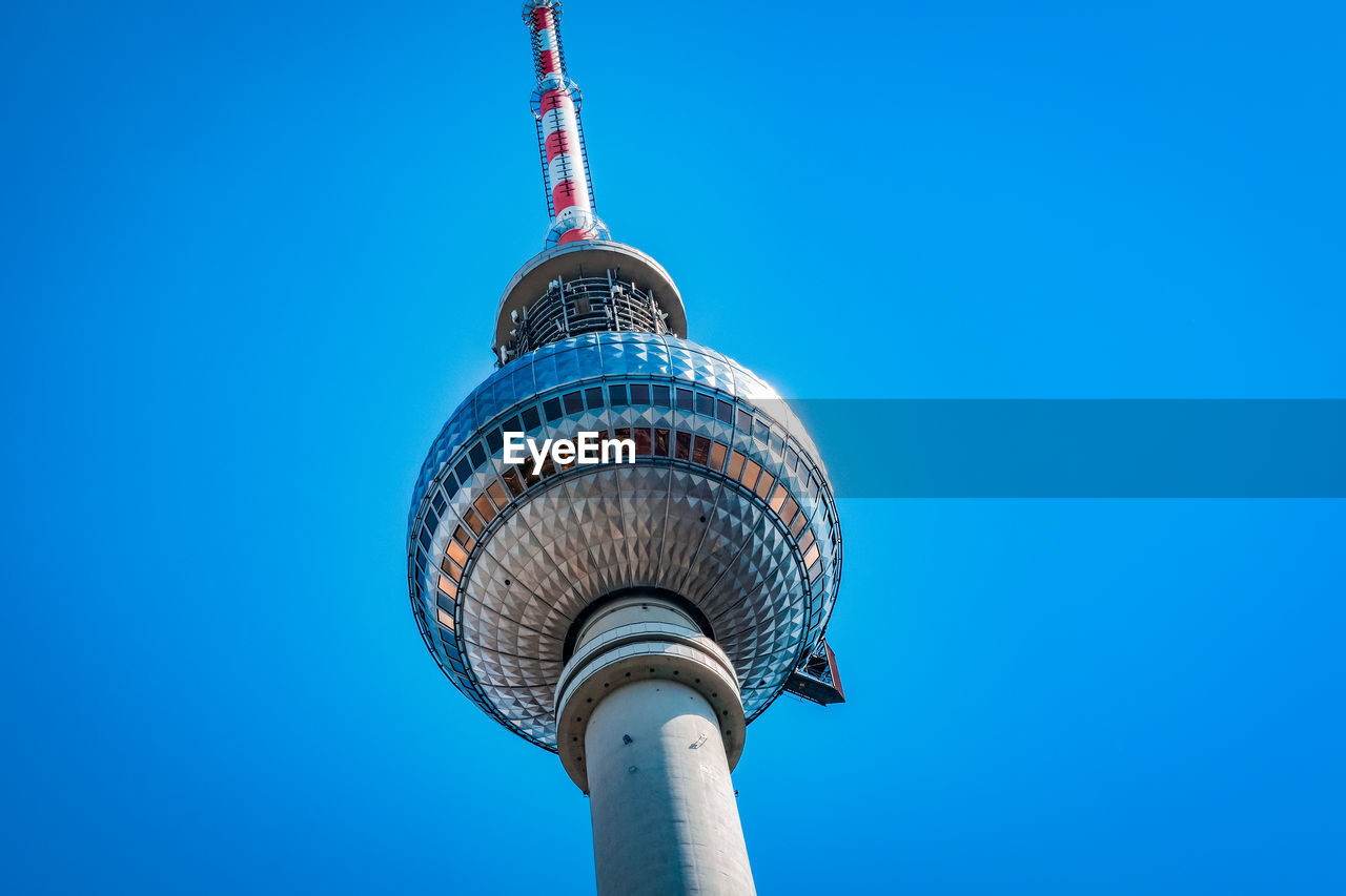 Low angle view of communications tower against blue sky