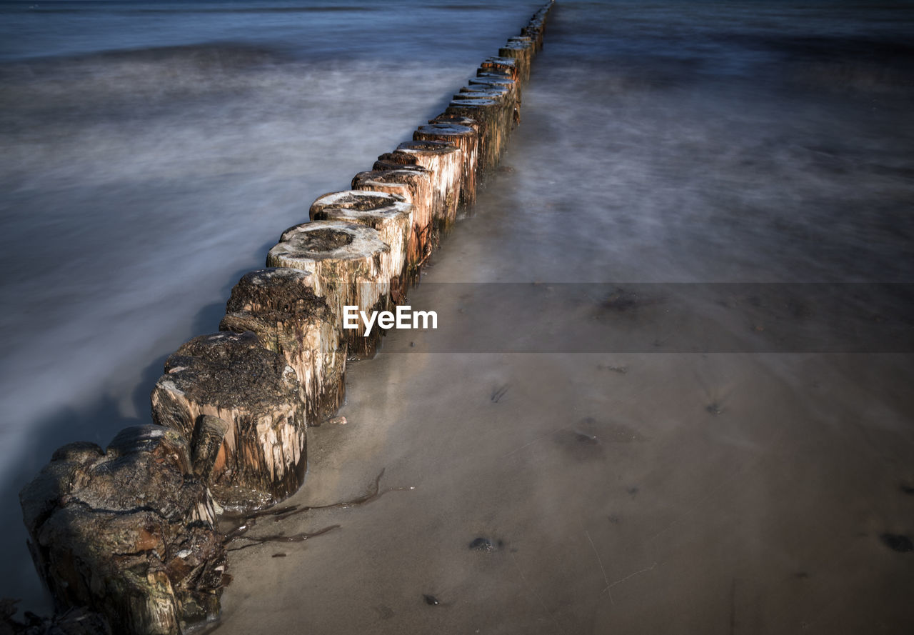HIGH ANGLE VIEW OF WOODEN POSTS ON SEA SHORE