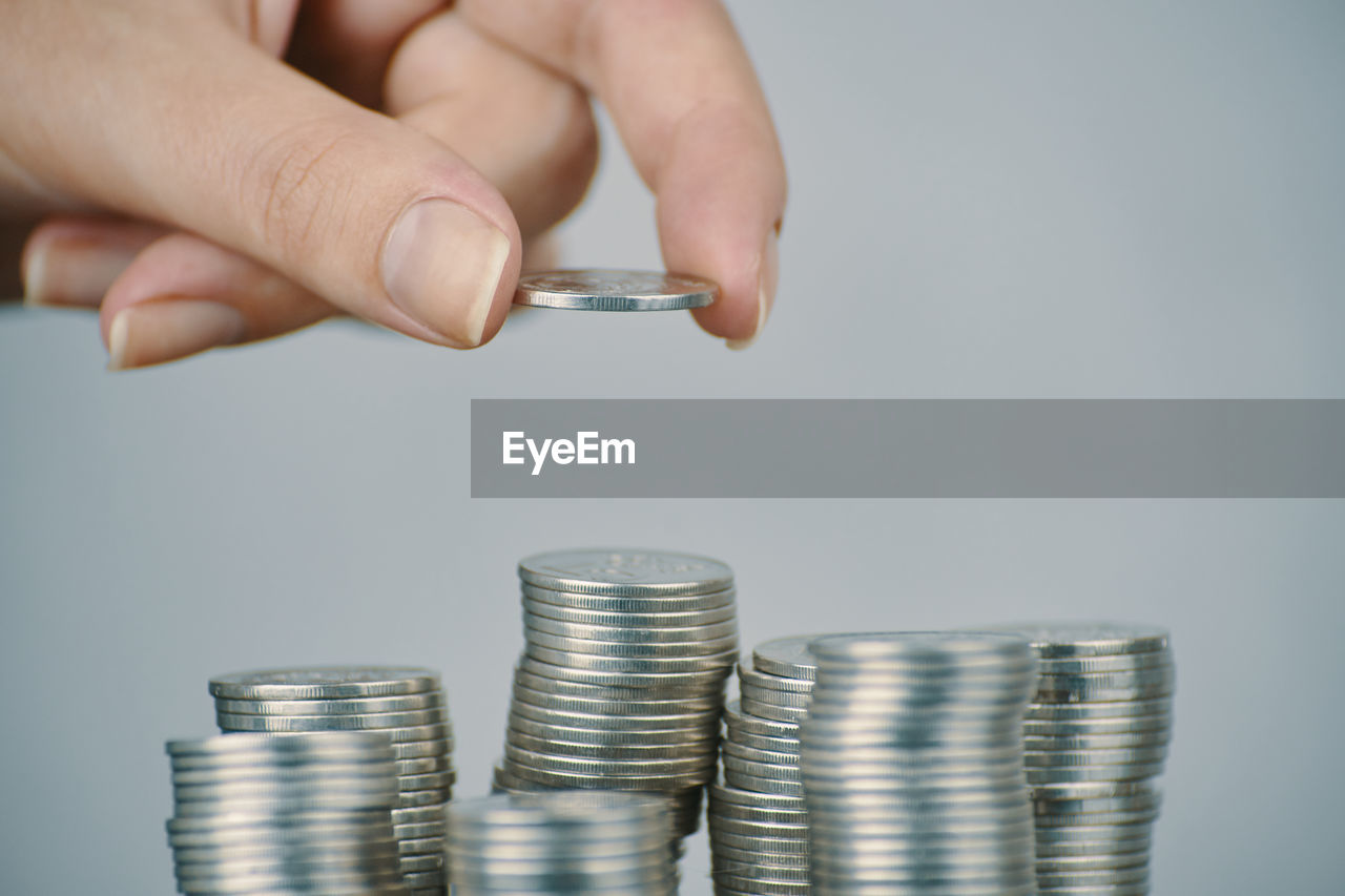 CLOSE-UP OF HAND HOLDING BLACK AND STACK OF COINS