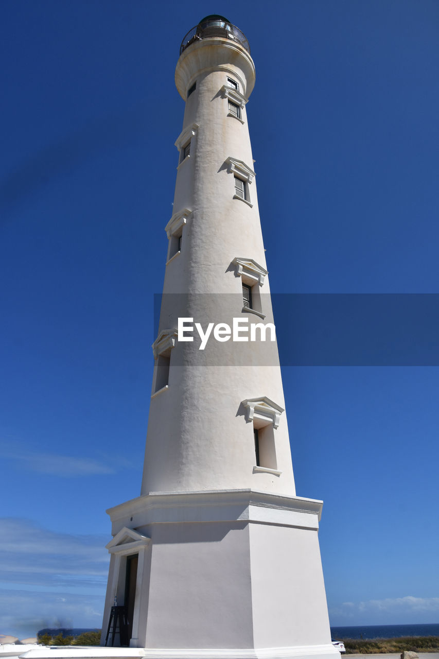 architecture, sky, blue, lighthouse, tower, built structure, nature, no people, building exterior, clear sky, water, travel, day, travel destinations, low angle view, building, history, outdoors, sunny, the past, land, guidance, sea, beach, sunlight, environment