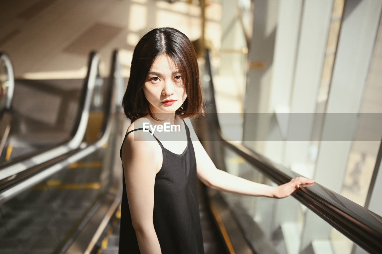 Portrait of woman standing on escalator