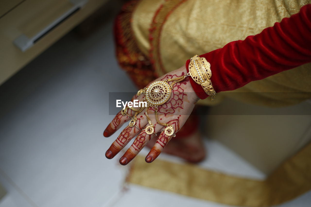 Low section of woman showing henna tattoo and jewelry on floor