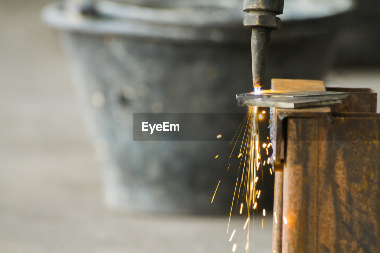 Cropped image of machine cutting sheet at workshop