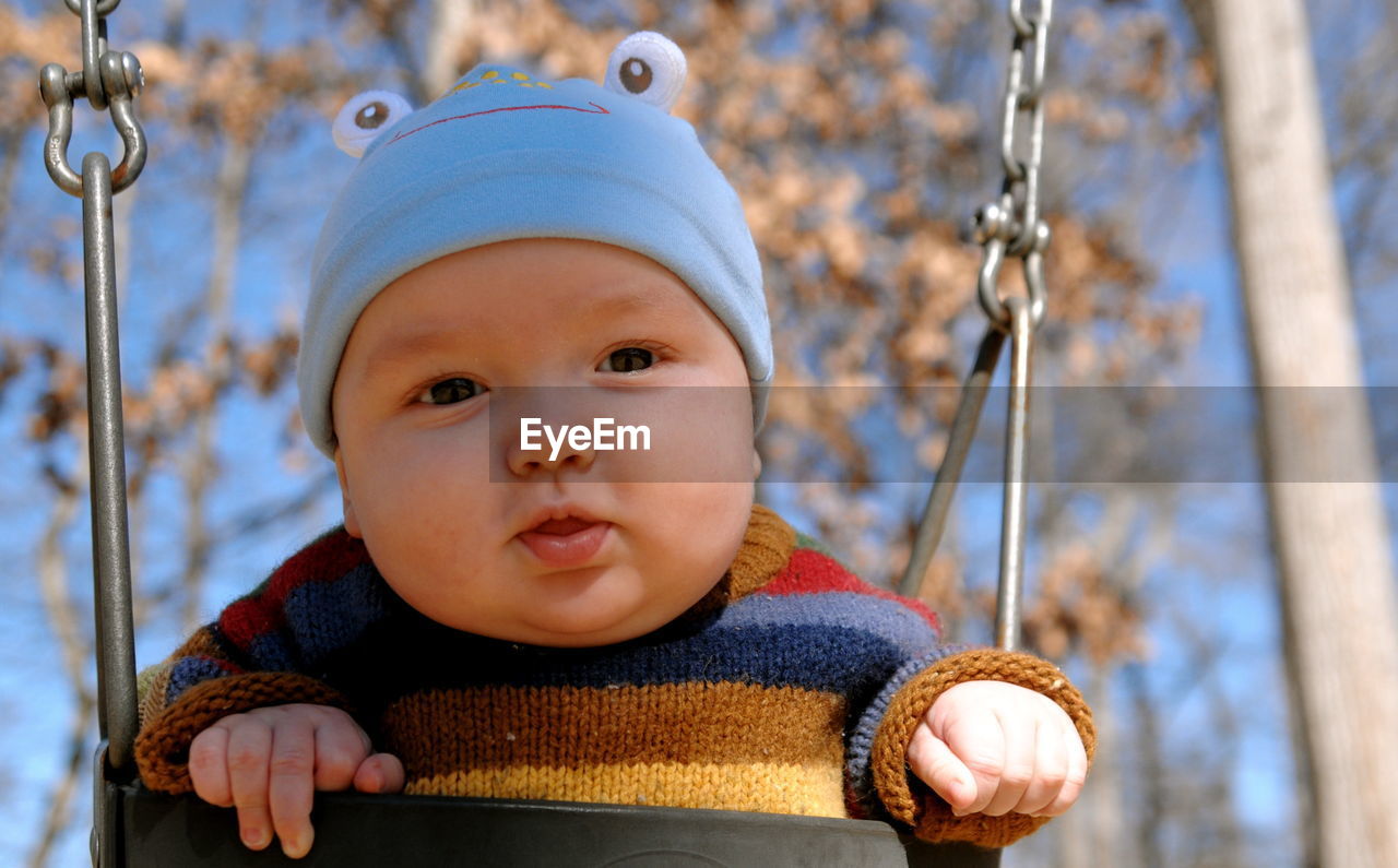 Close-up portrait of baby on swing at playground