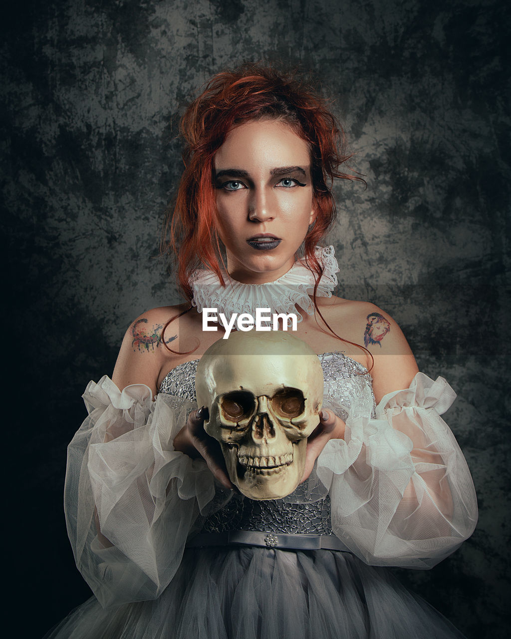 Fine art photography of a woman handling a skull in a dark background