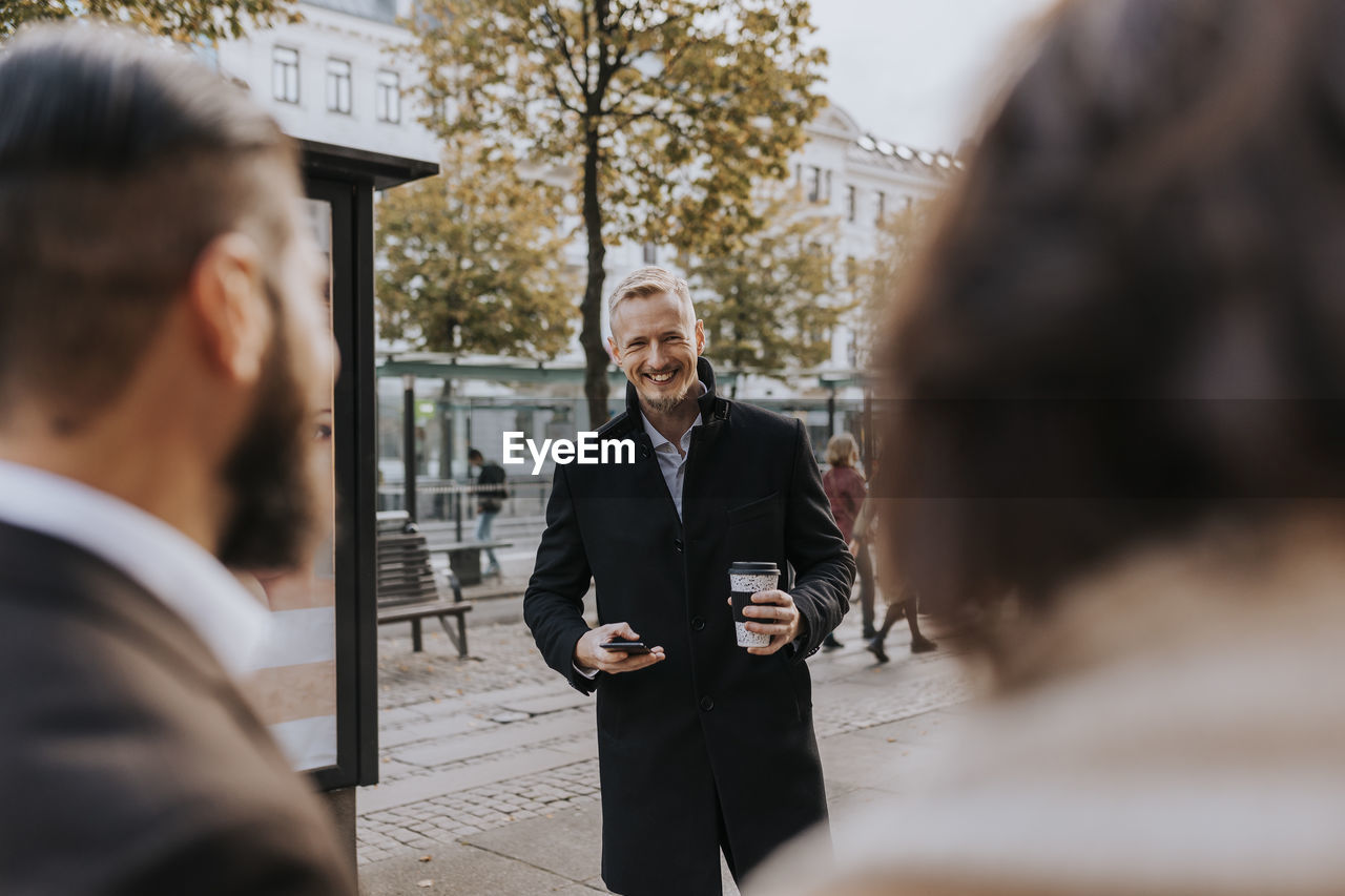 Smiling businessman holding disposable cup