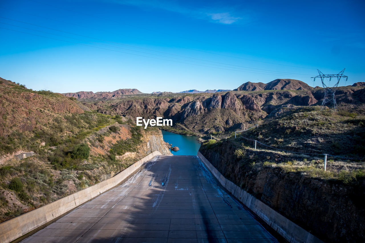 Road amidst mountains against clear blue sky