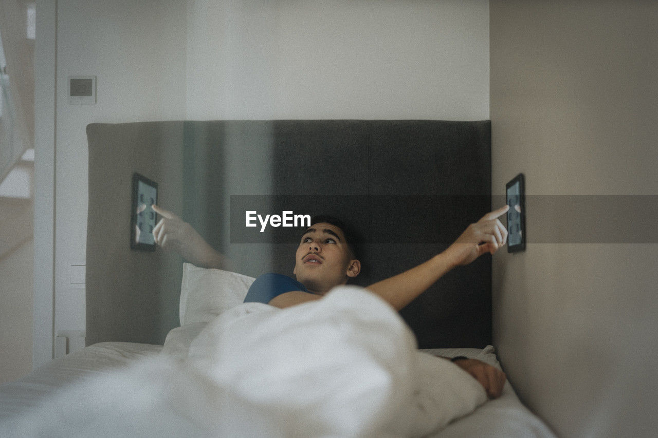 Boy adjusting temperature of bedroom through digital tablet at modern home