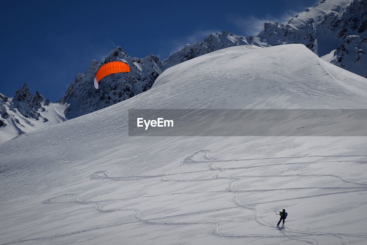 Person kiteboarding on snow covered mountain