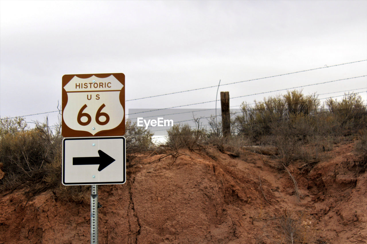 Close-up of arrow sign on landscape