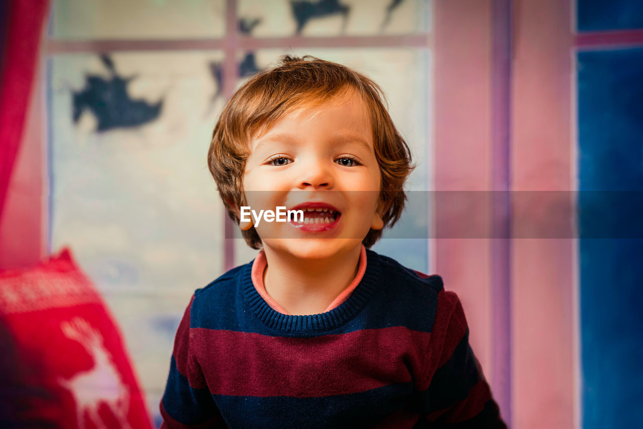 Closeup of an child with a happy face and blue eyes with a christmas background. merry christmas.