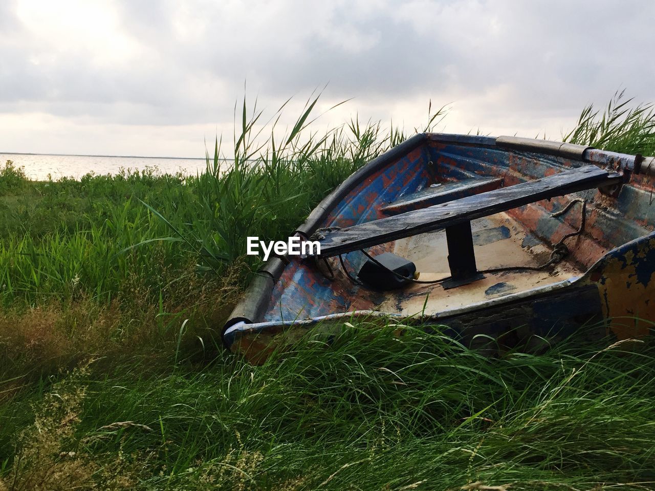 Abandoned boat on field against sky