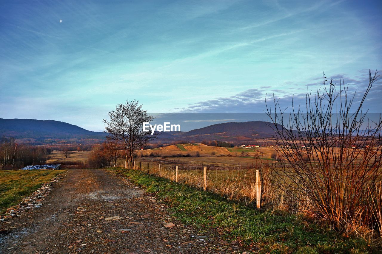 Road amidst field against sky