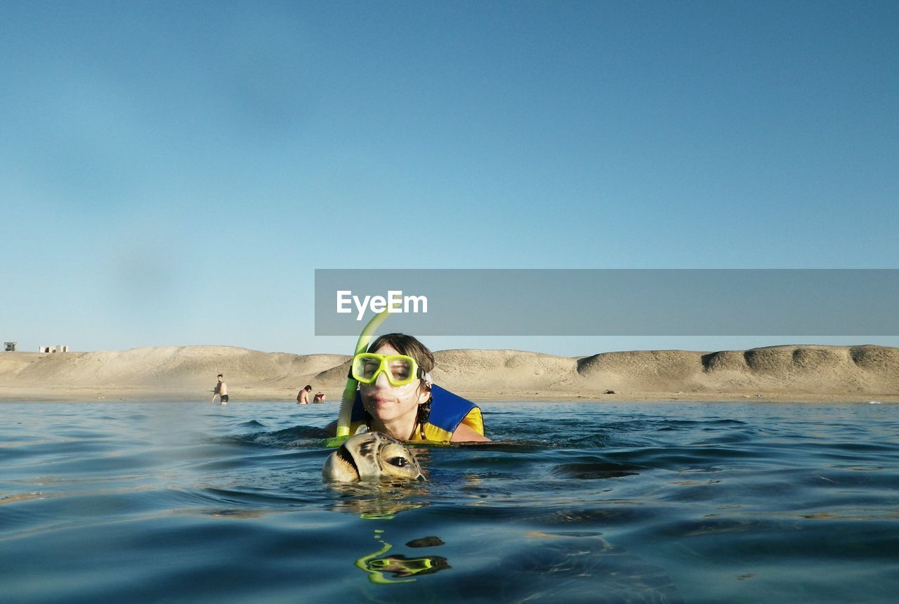 Man snorkeling in sea against blue sky during sunny day