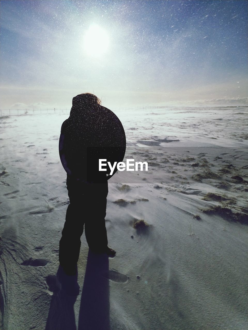 REAR VIEW OF SILHOUETTE MAN STANDING ON BEACH AGAINST SKY