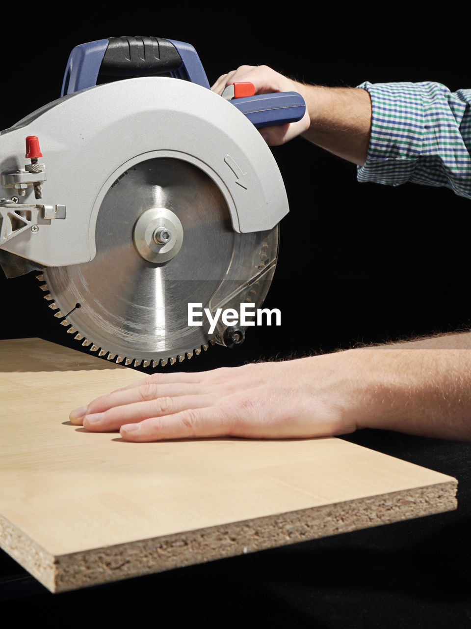 Cropped hand of man working with machinery against black background