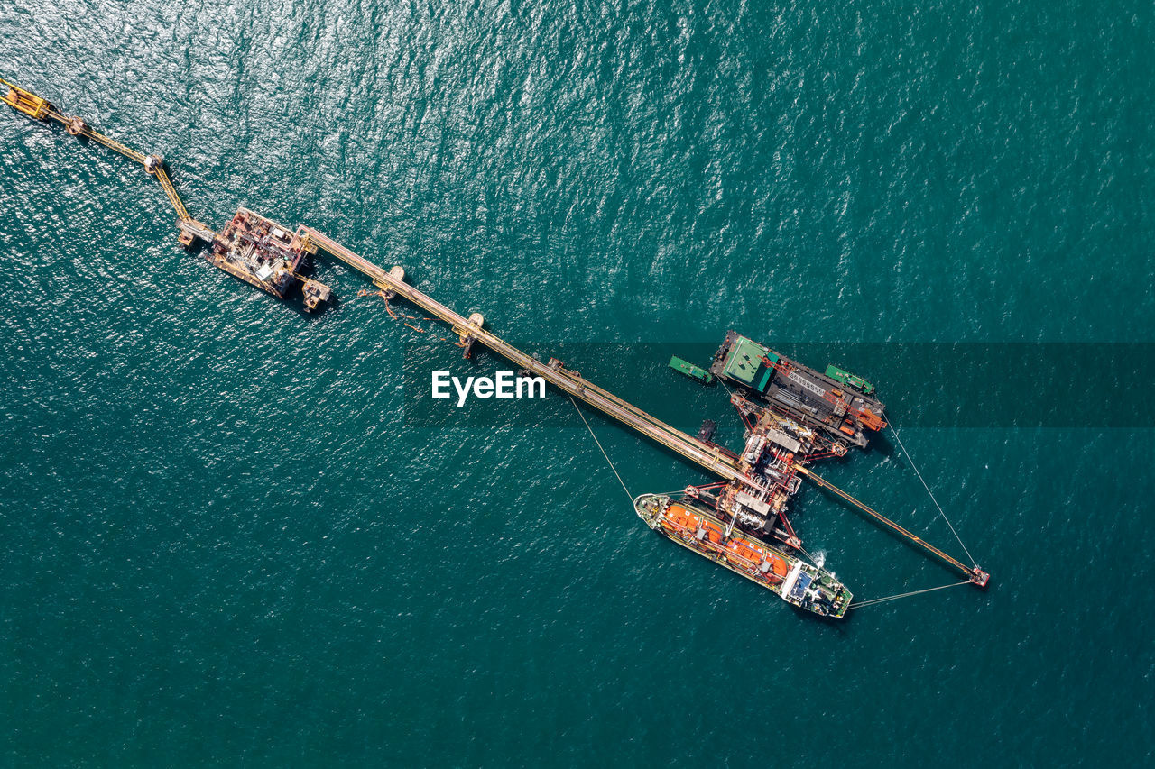 Aerial view oil pipes to oil tanker ships at pier off the coast in beautiful peaceful environment.