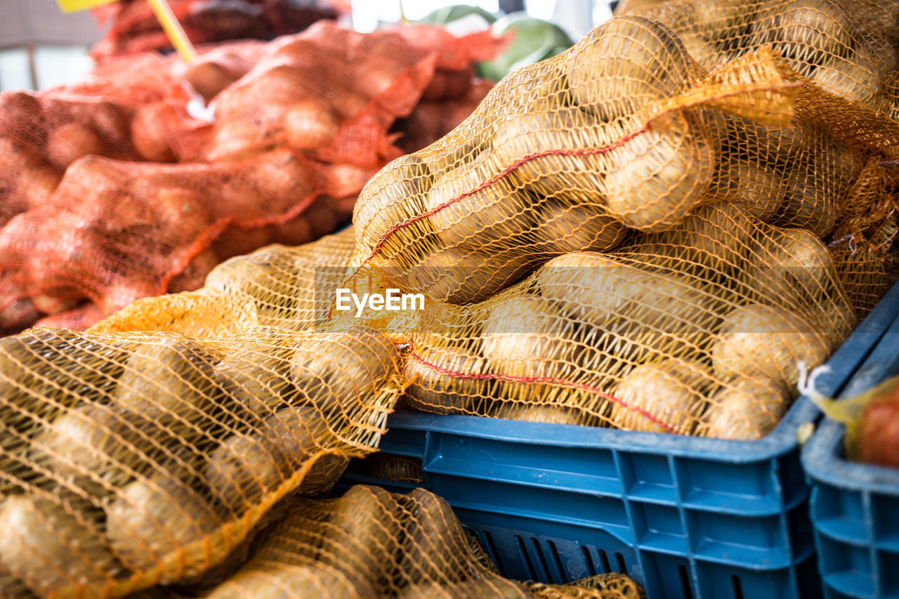 High angle view of potatoes and onions in crates at market stall