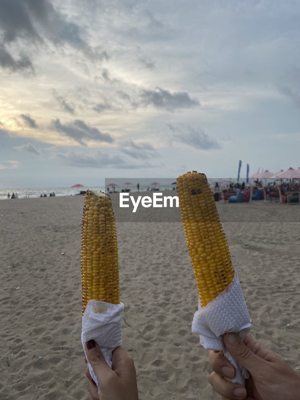 WOMAN HOLDING UMBRELLA ON BEACH AGAINST SKY