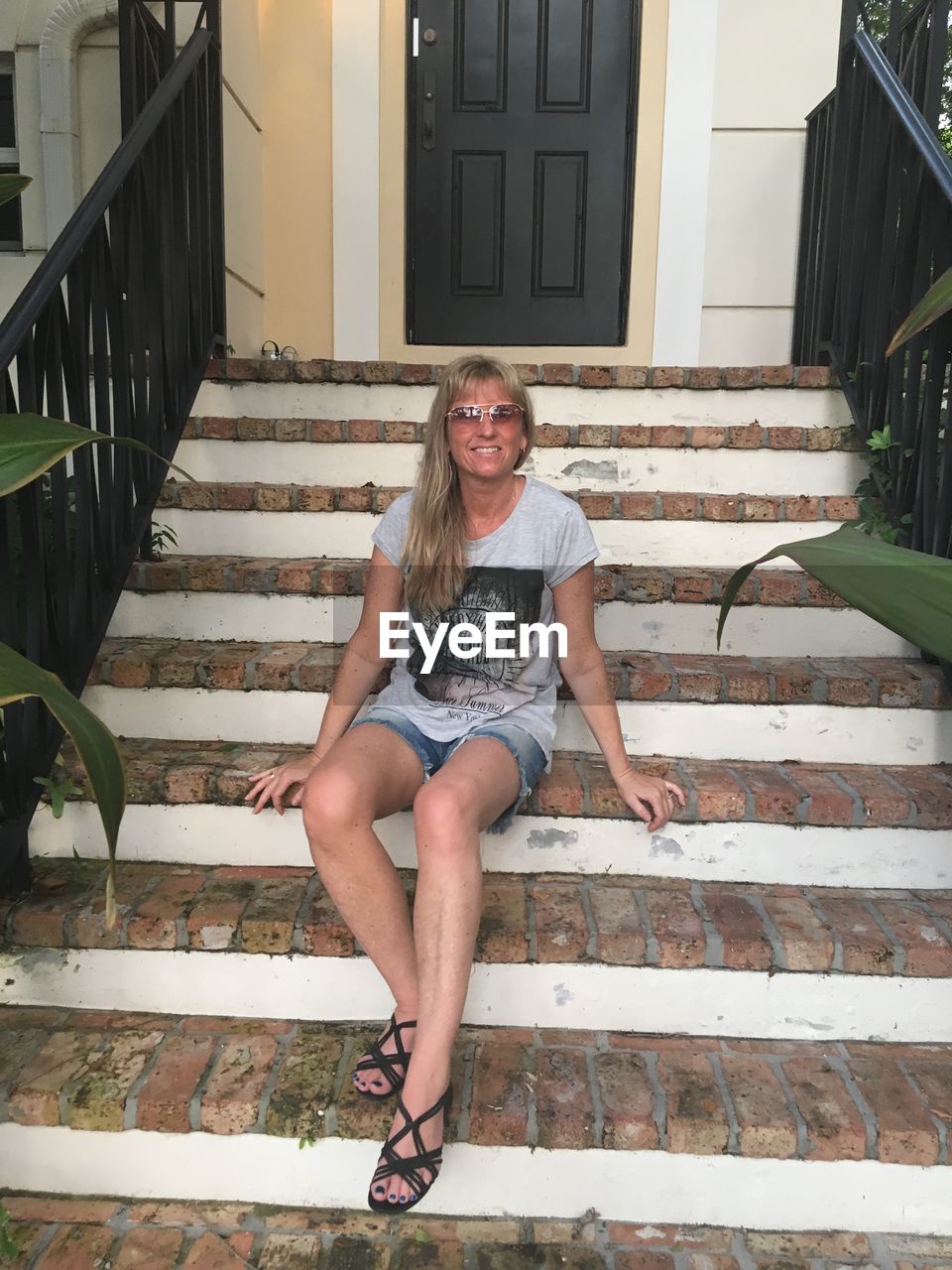 PORTRAIT OF HAPPY WOMAN SITTING ON STAIRCASE