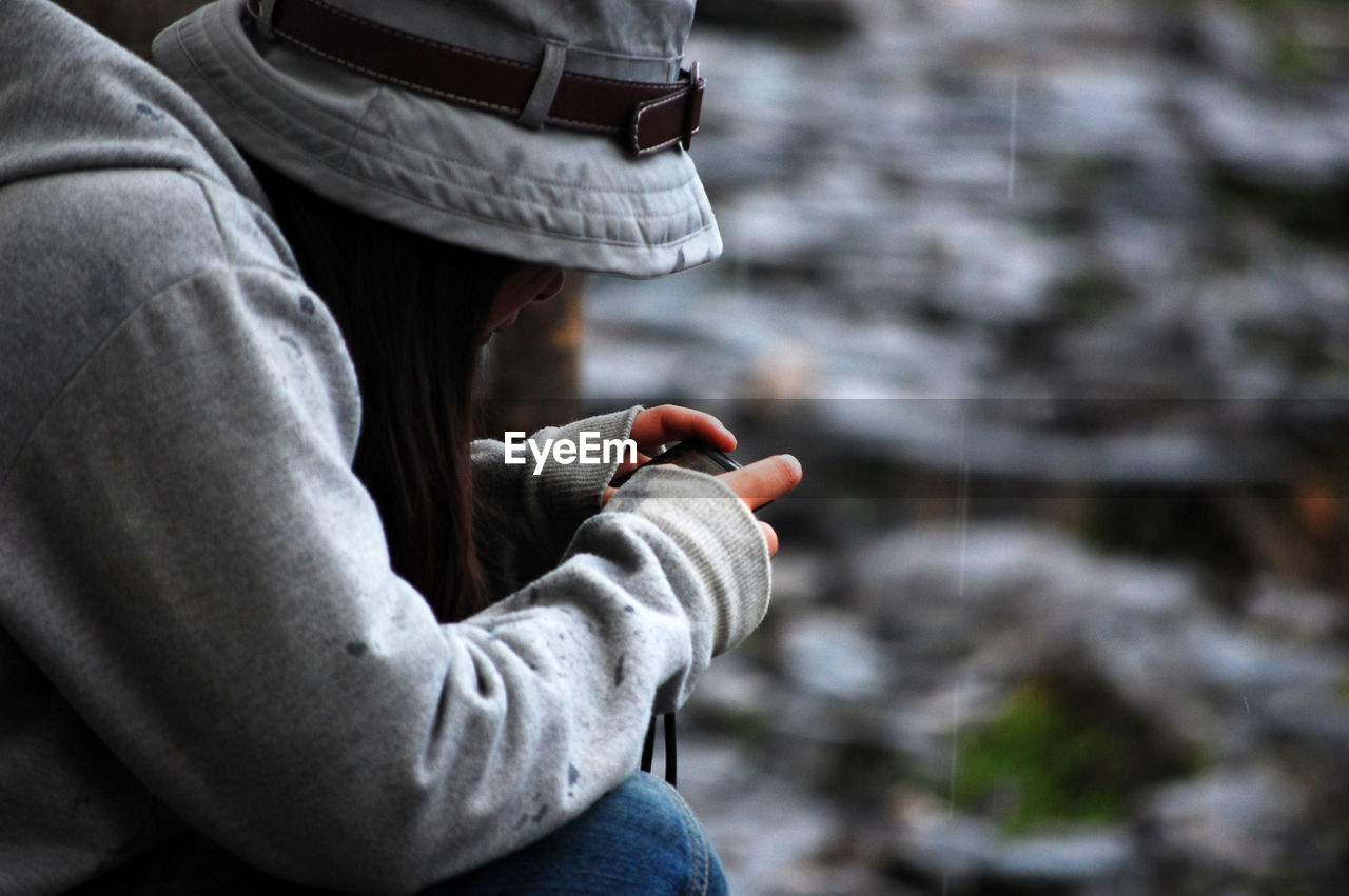 Side view of woman using mobile phone while sitting outdoors