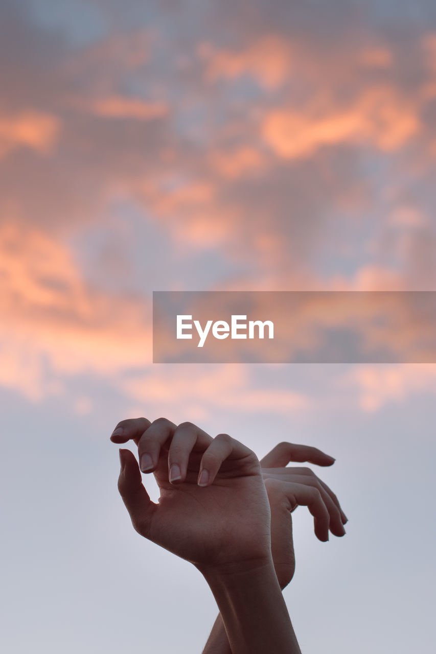 Person holding umbrella against sky during sunset