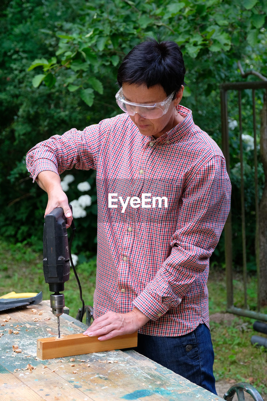 Carpenter using drill outdoors