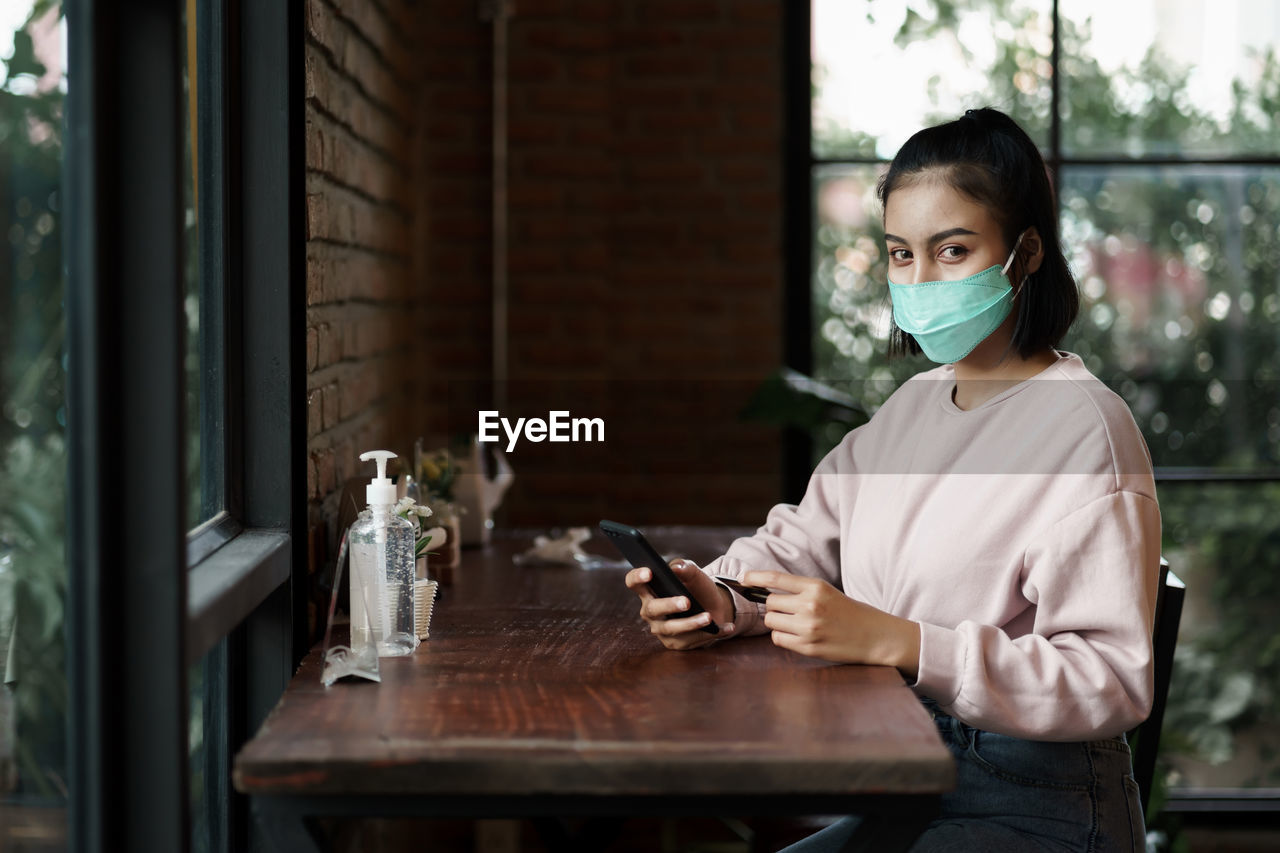 Portrait of young woman using smart phone in cafe