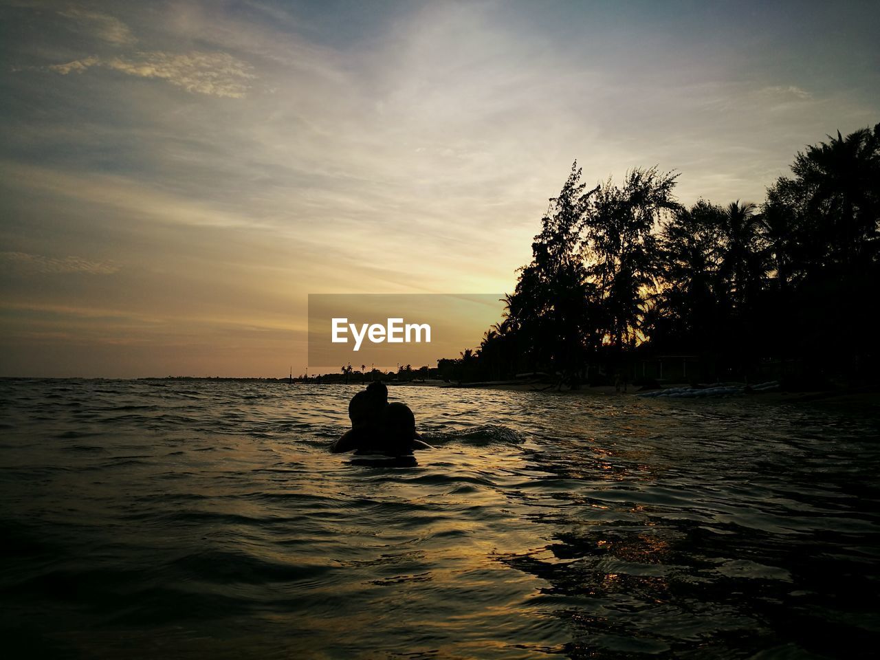 SILHOUETTE PERSON IN SEA AGAINST SKY DURING SUNSET