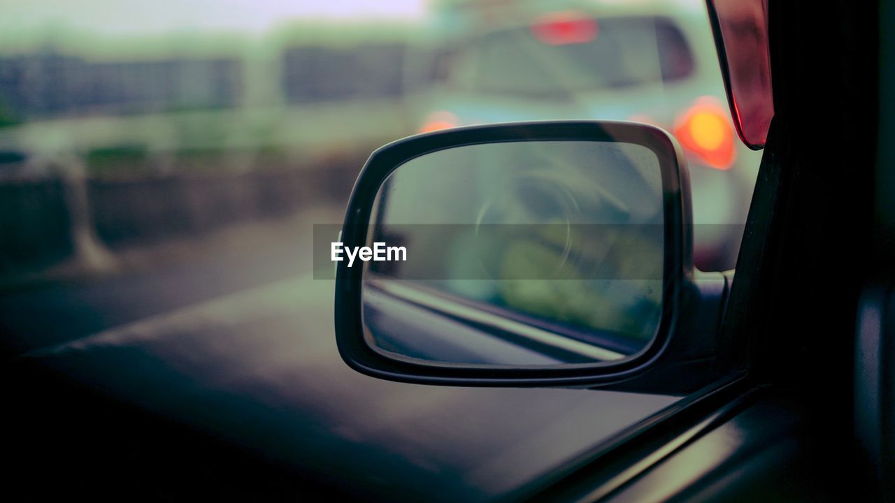 Close-up of side-view mirror seen through car window