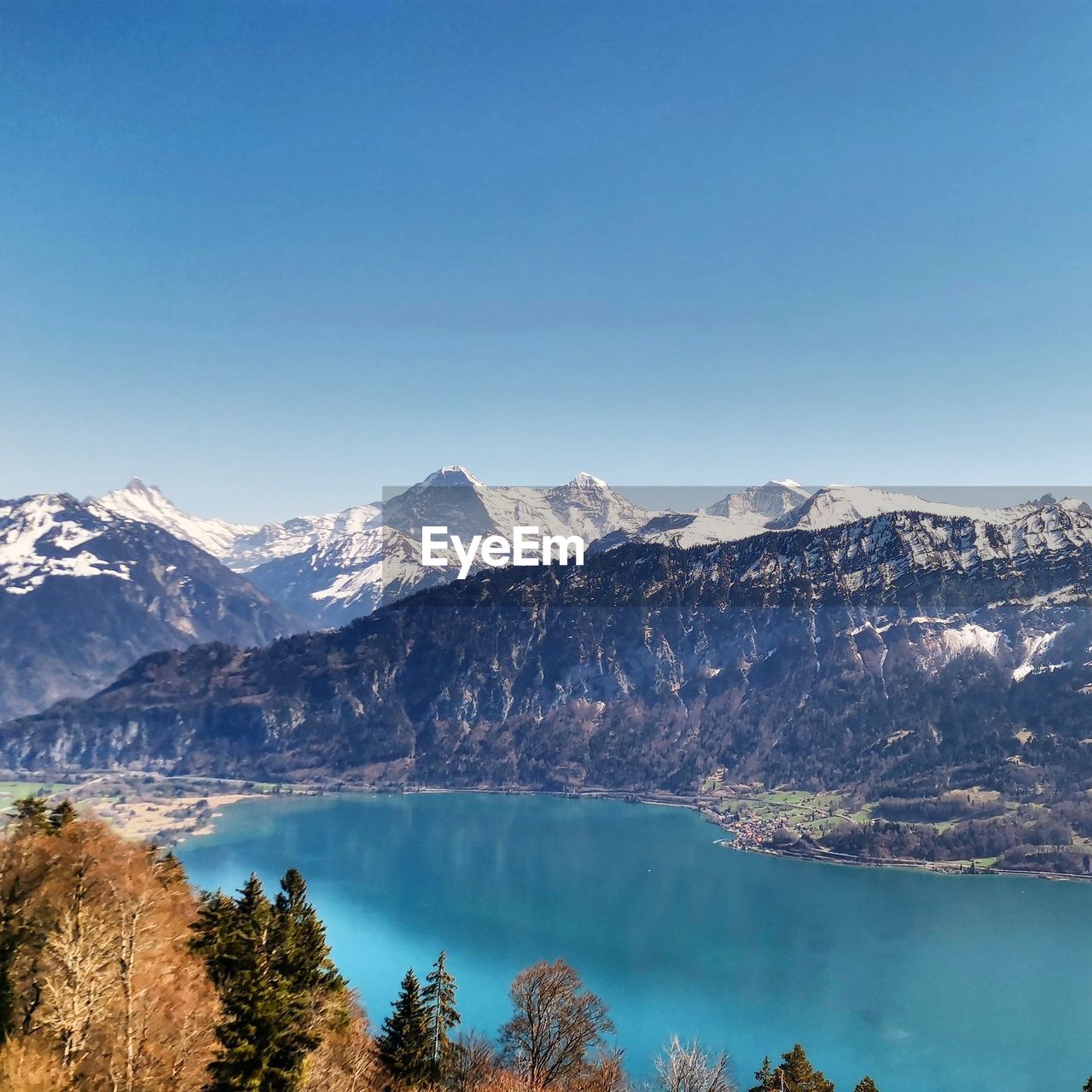 Scenic view of lake and snowcapped mountains against clear blue sky