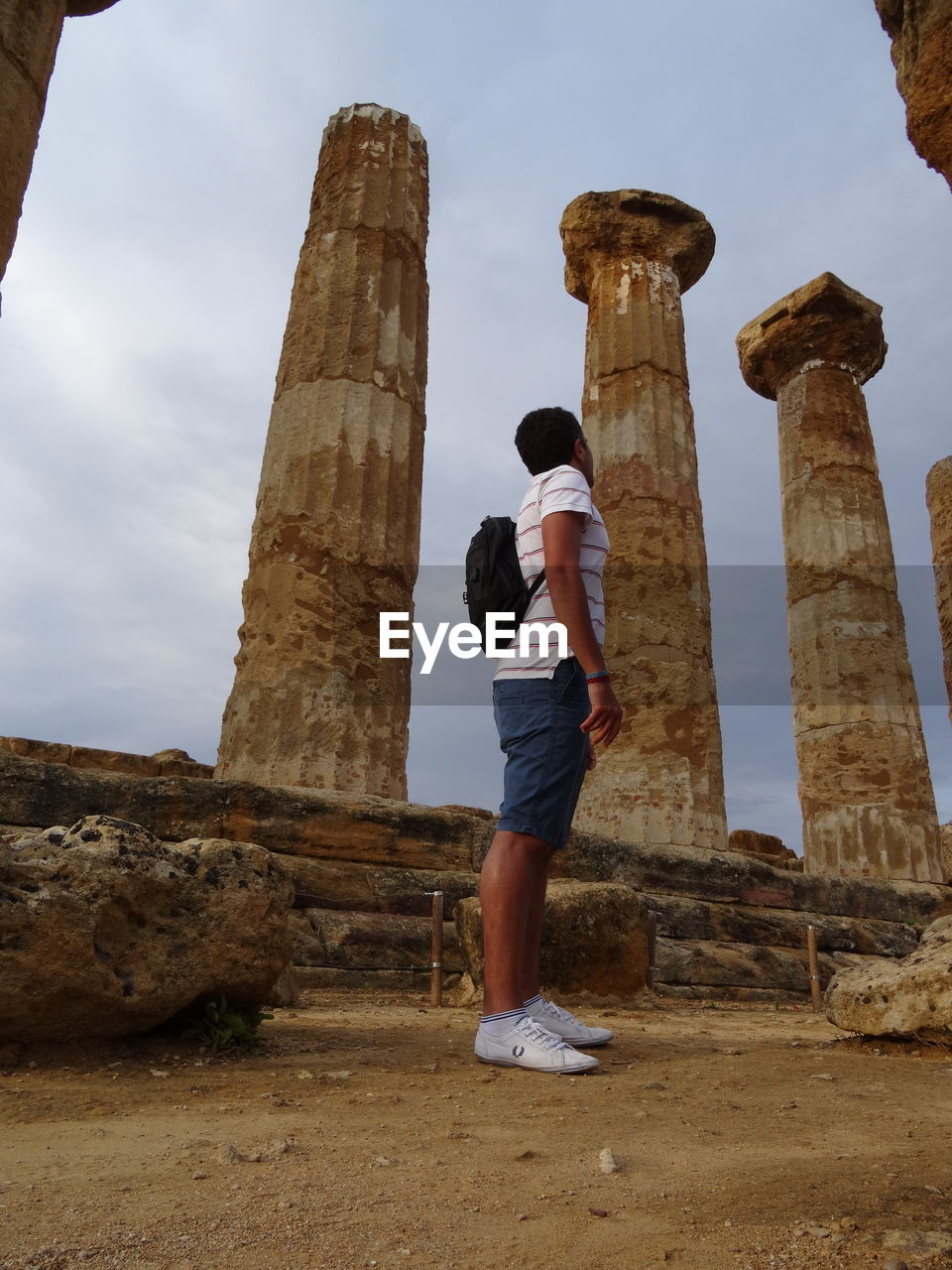 LOW ANGLE VIEW OF MAN STANDING ON OLD RUIN