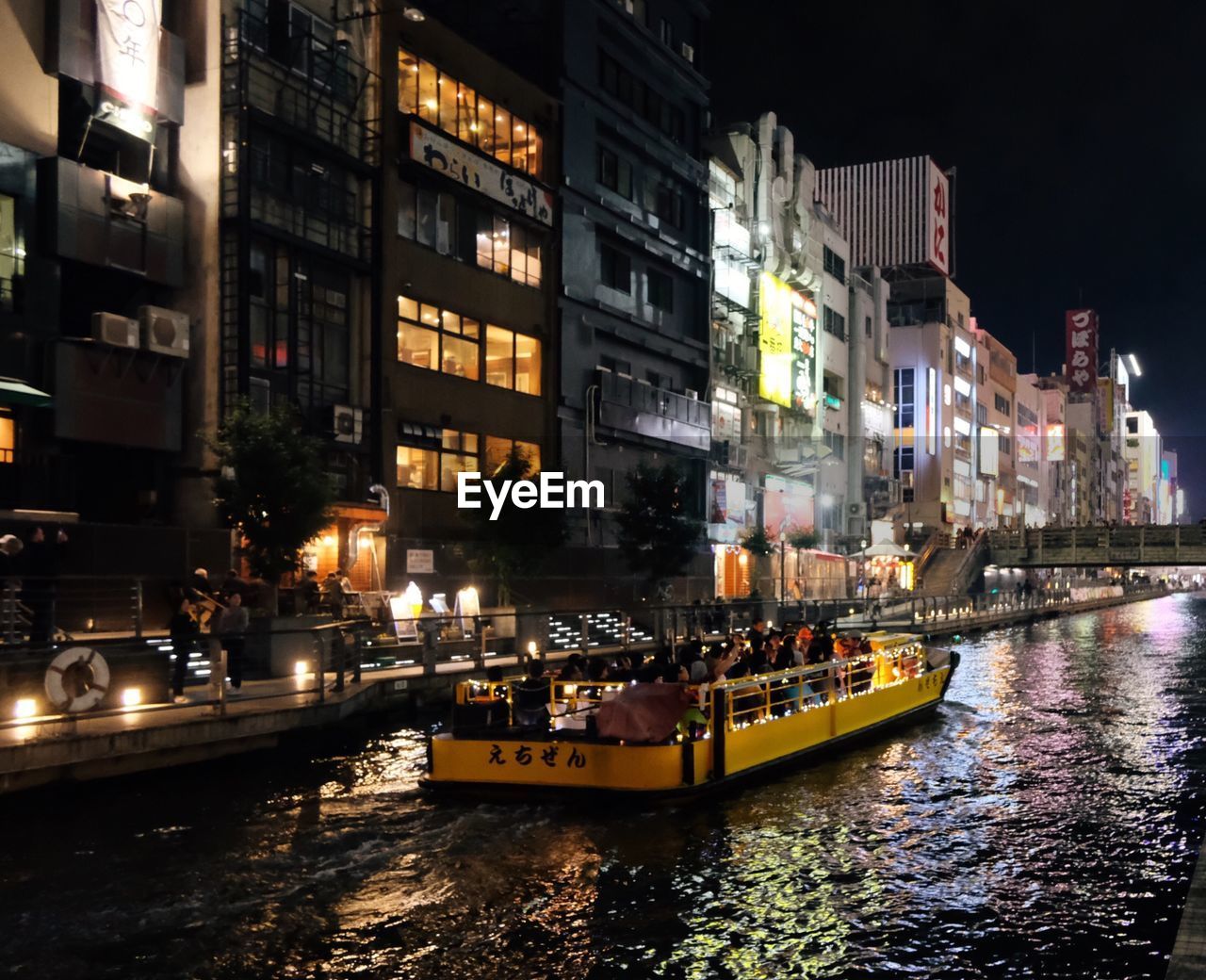 BOATS IN RIVER AGAINST ILLUMINATED BUILDINGS IN CITY
