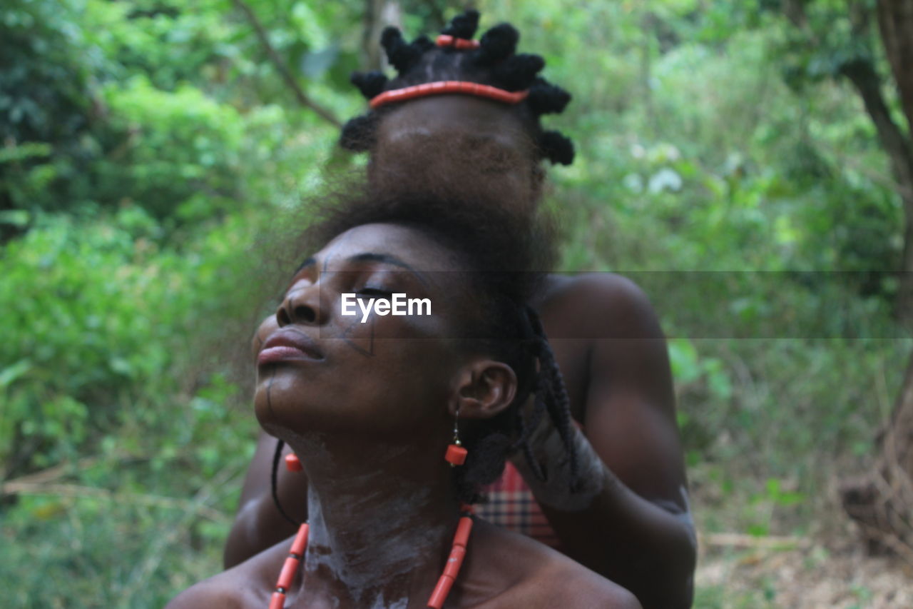 Woman braiding friend hair in forest