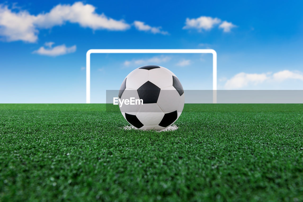 Digital composite of soccer ball on playing field against sky 
