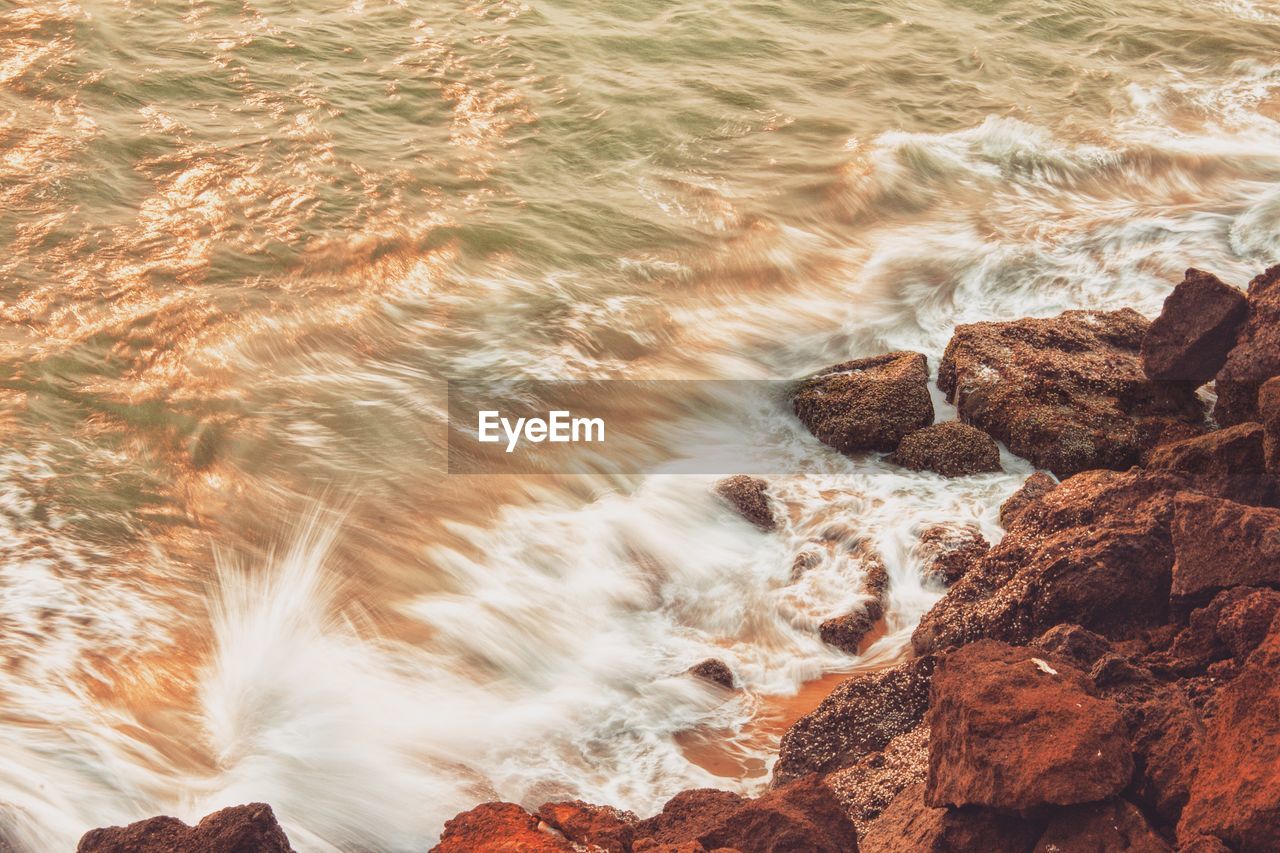 High angle view of waves breaking on rocks