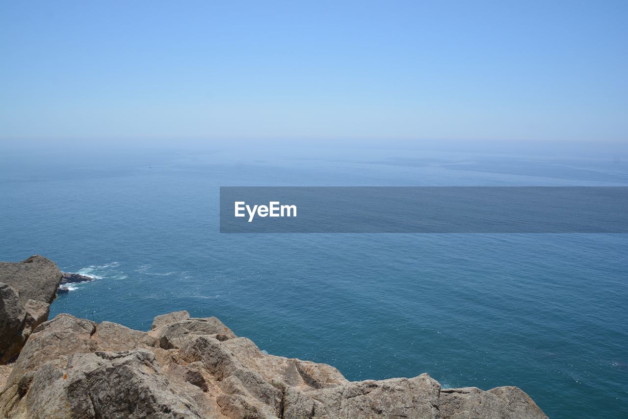 SCENIC VIEW OF ROCKS BY SEA AGAINST BLUE SKY