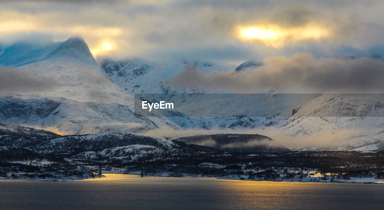 Scenic view of mountains against cloudy sky during sunset