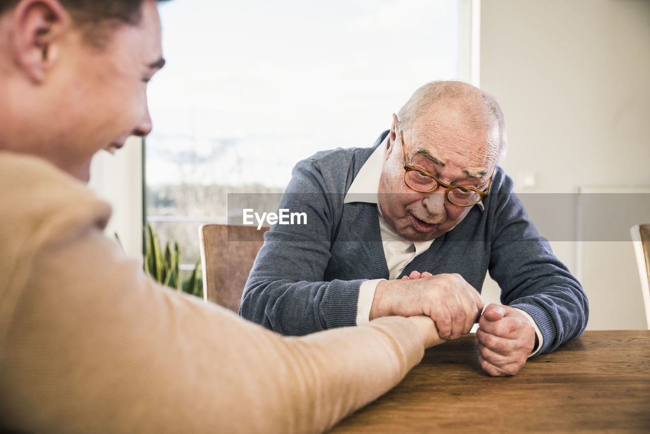 Senior man and young man arm wrestling