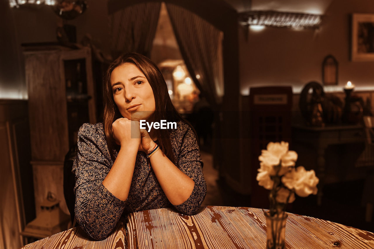 Emotions of lonely woman at cafe at the table drinking tea in the evening at cafe romantic light