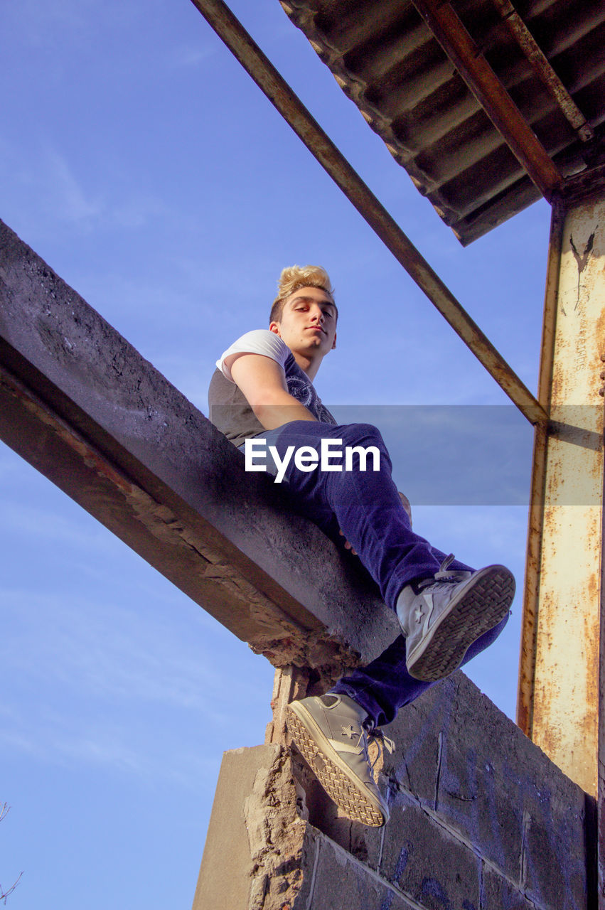 LOW ANGLE VIEW OF YOUNG MAN LOOKING AWAY