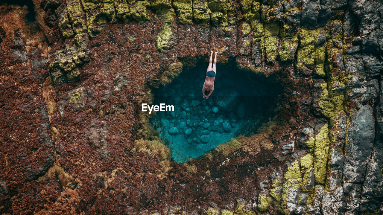 High angle view of shirtless man diving in sea against sky