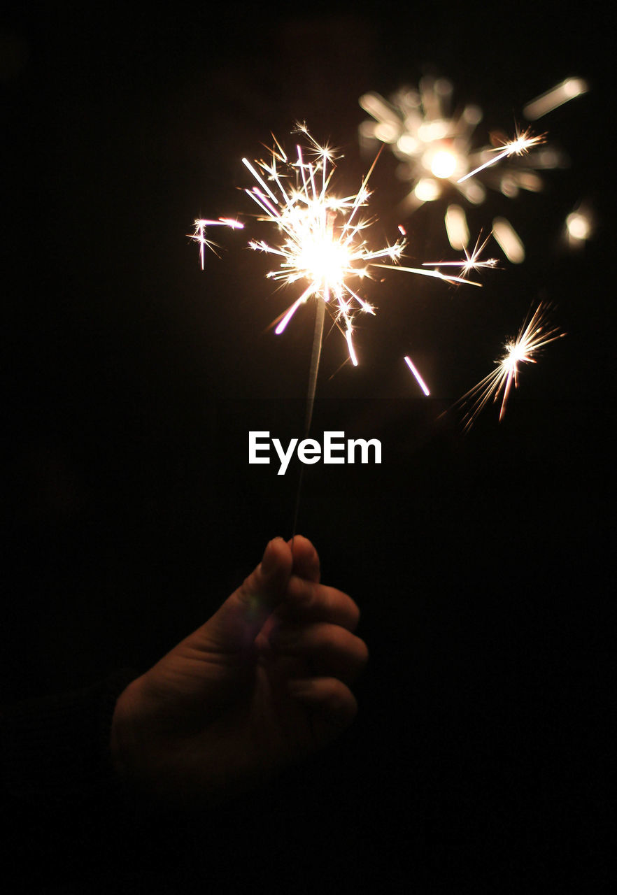Close-up of person holding sparklers at night
