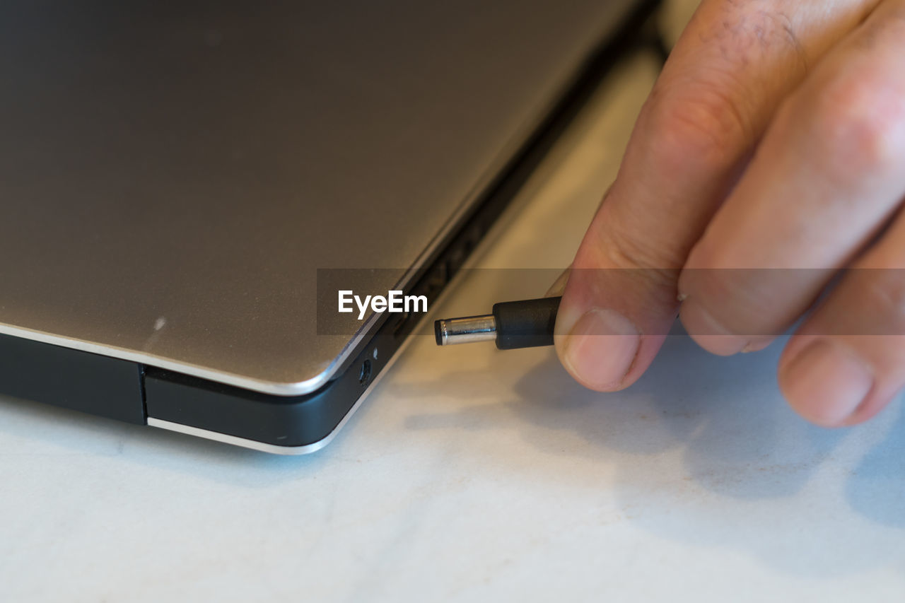 HIGH ANGLE VIEW OF PERSON USING LAPTOP ON TABLE