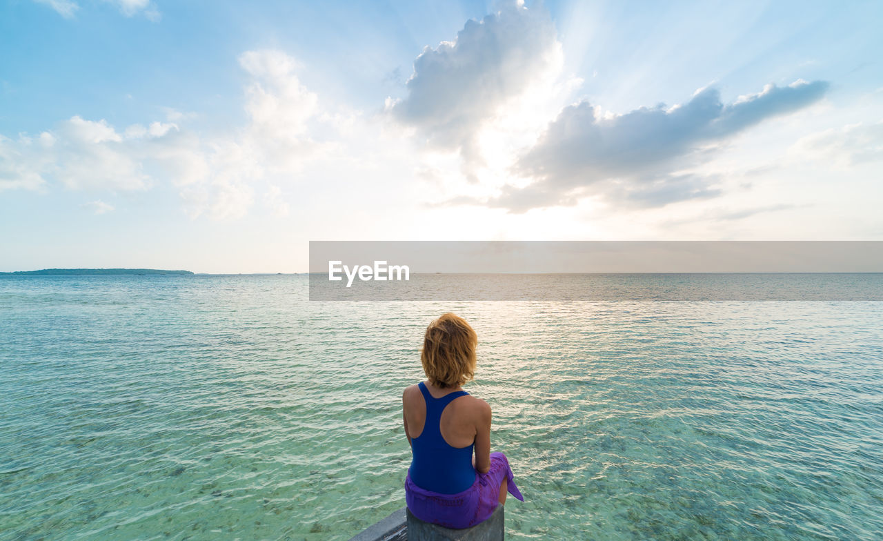 Woman looking at sea against sky