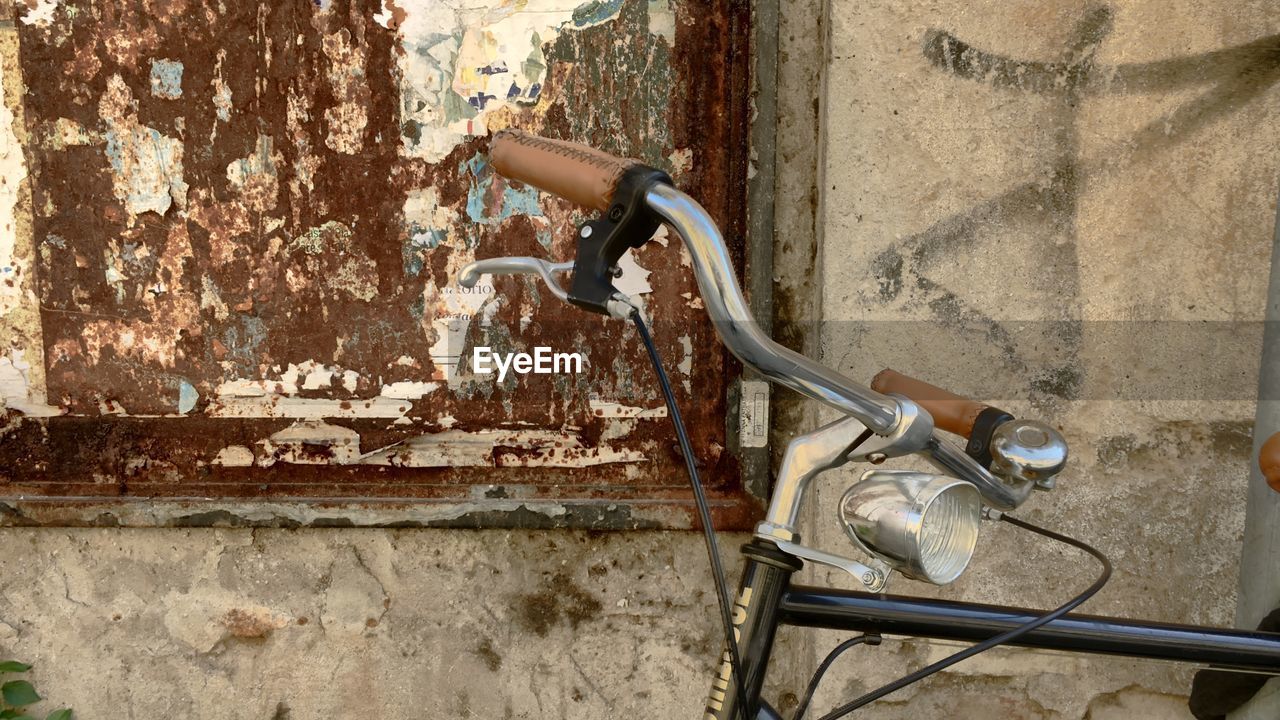 CLOSE-UP OF ABANDONED BICYCLE AGAINST WALL