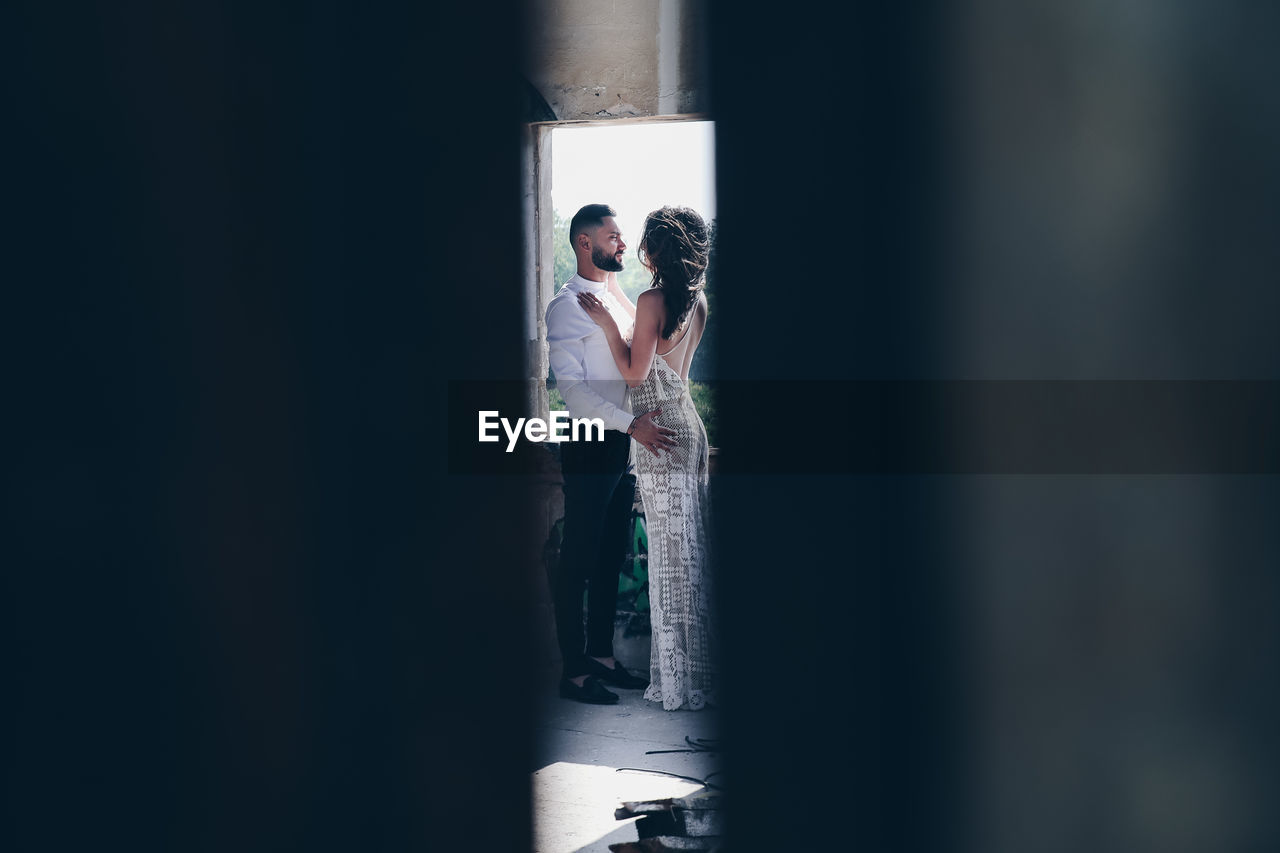 COUPLE STANDING IN FRONT OF A WOMAN
