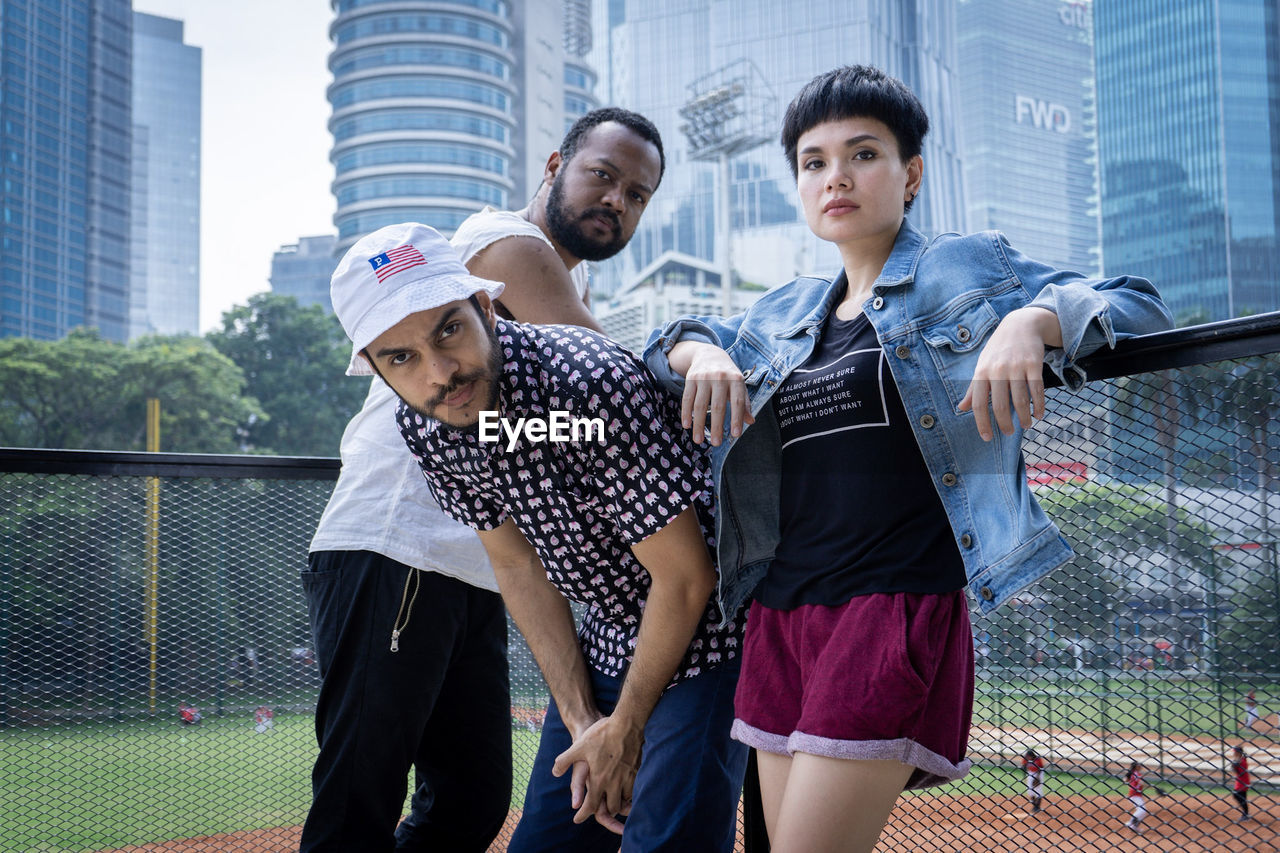 PORTRAIT OF FRIENDS STANDING AT OFFICE BUILDING