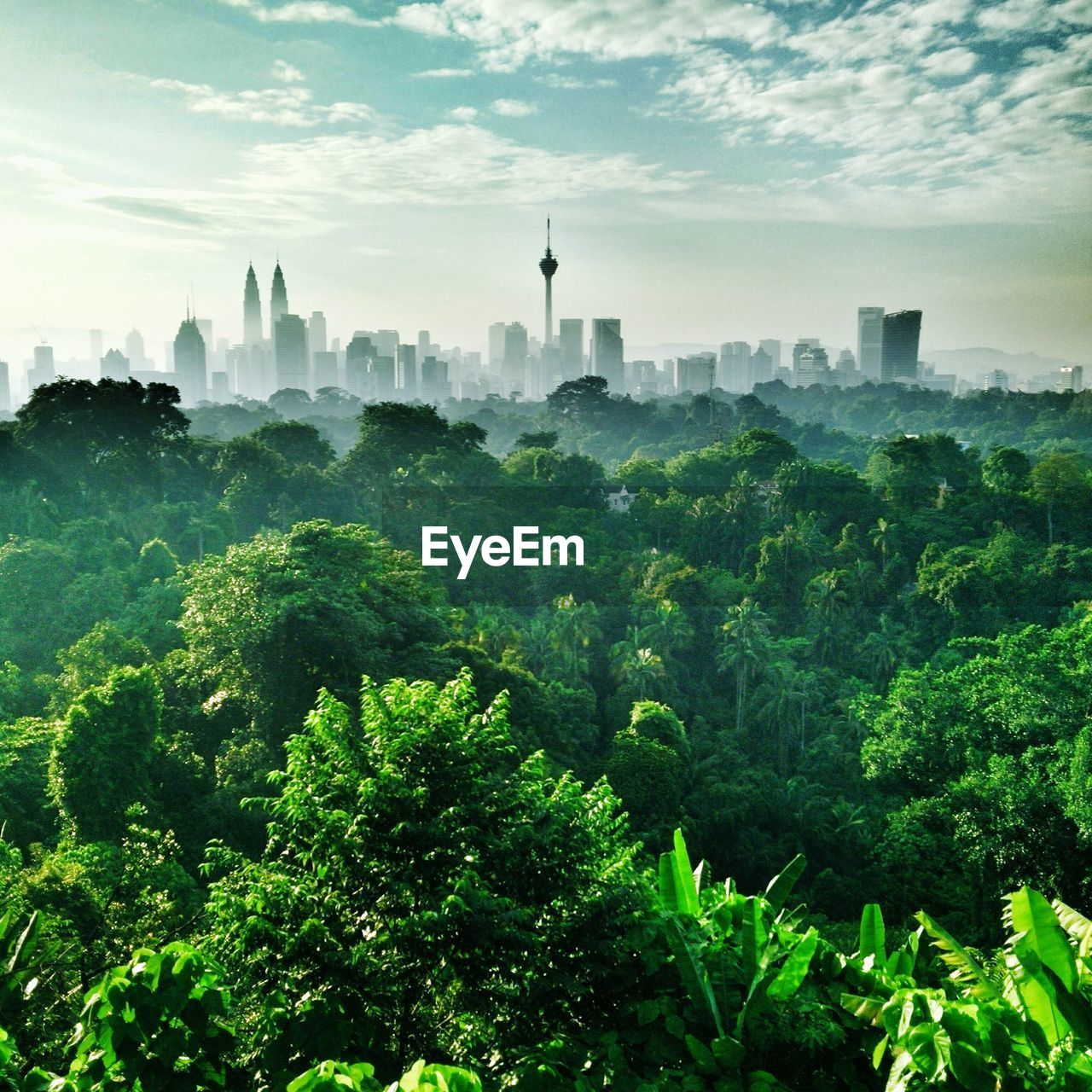 Menara kuala lumpur tower amidst buildings in front of trees against sky